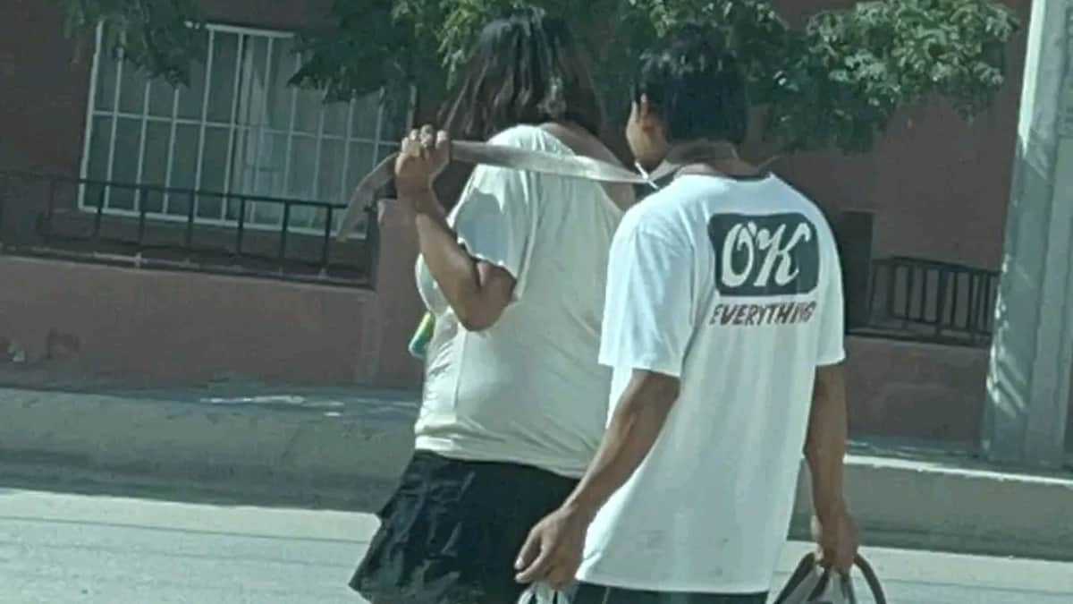 VIDEO: Mujer amarra con un cinturón a su pareja y lo pasea sonriente por las calles