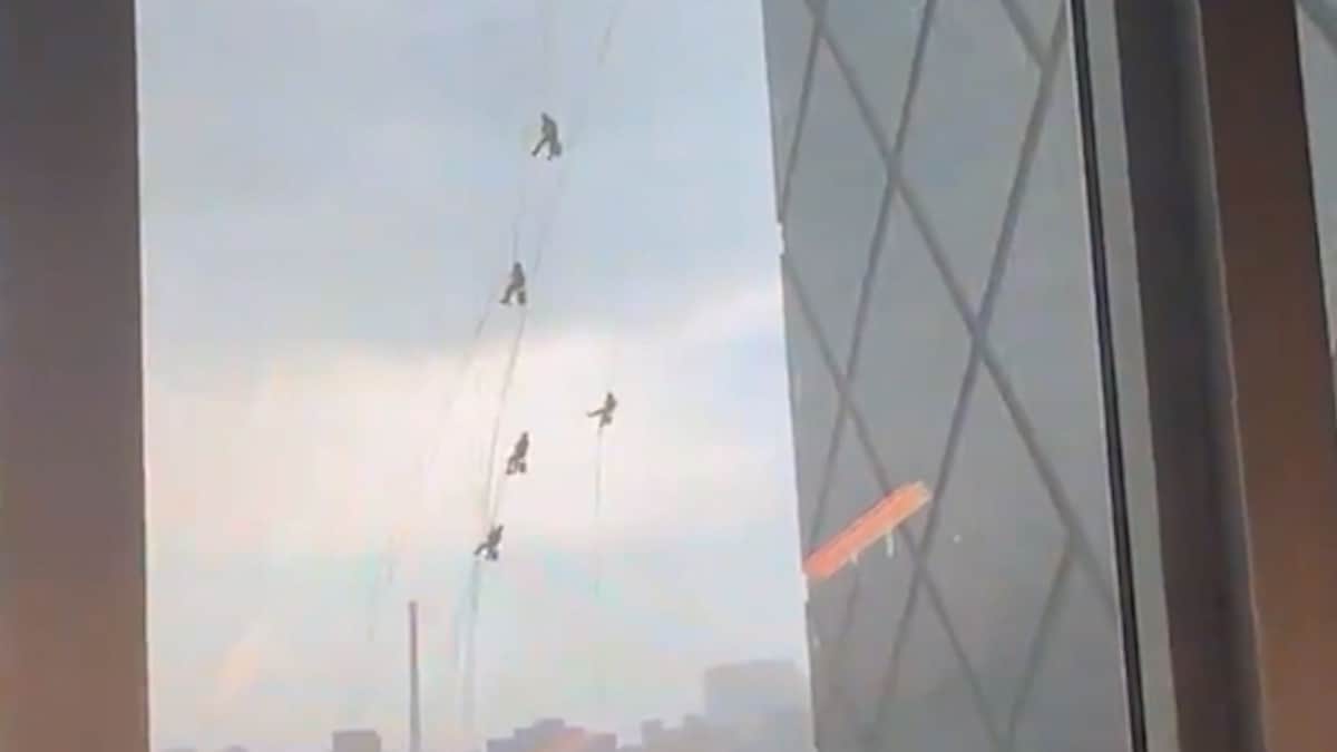 Limpiaventanas cuelgan de torre de Beijing, China, durante una tormenta