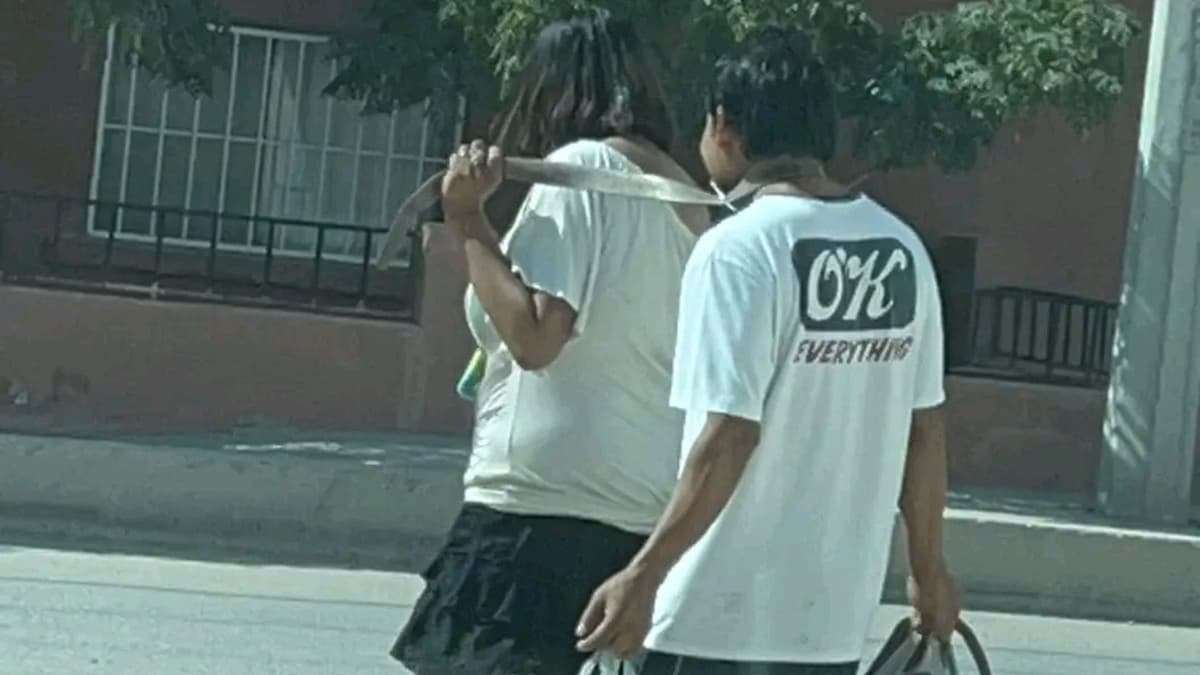 VIDEO: Mujer amarra con un cinturón a su pareja y lo pasea sonriente por las calles