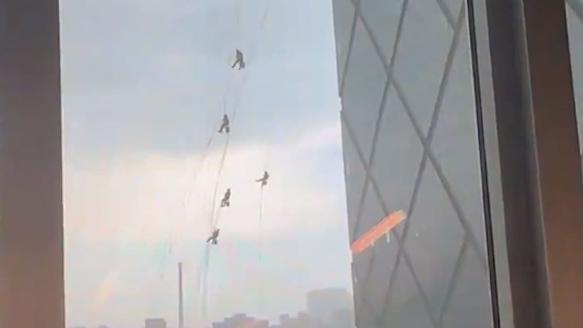 Limpiaventanas cuelgan de torre de Beijing, China, durante una tormenta