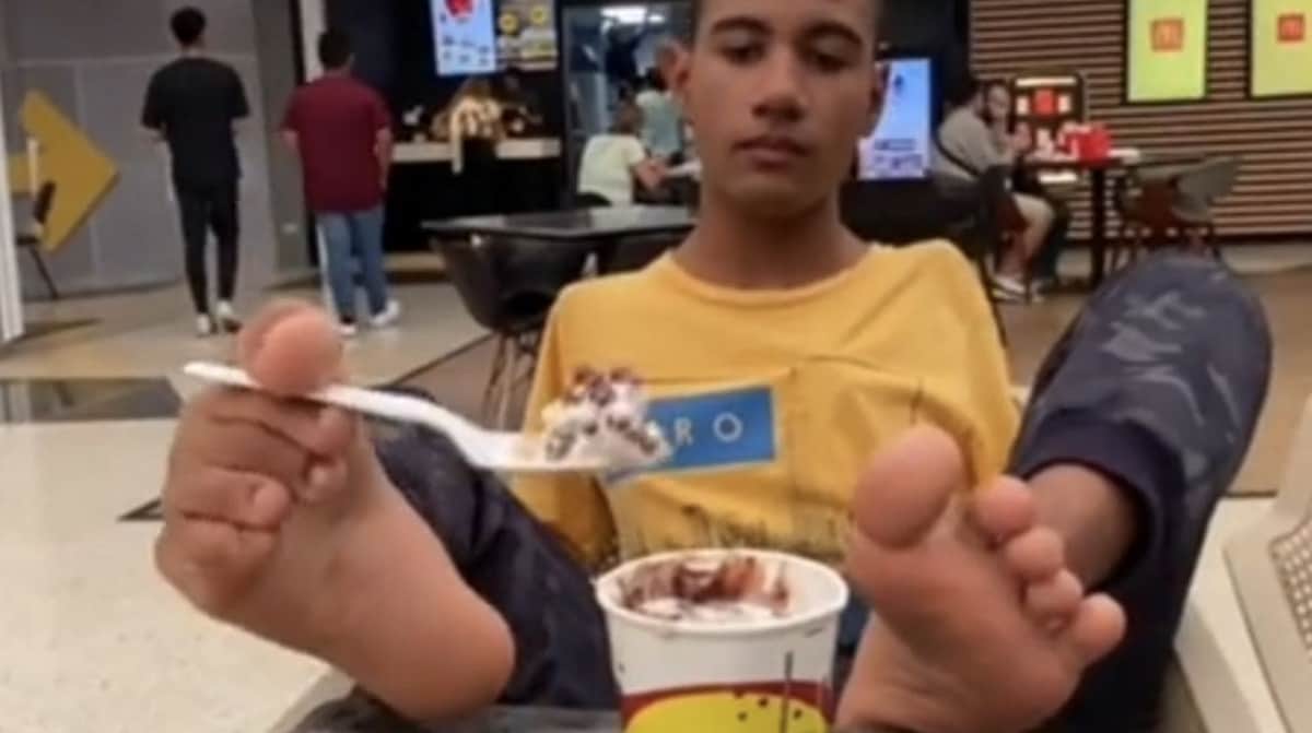Mujer regaña a joven por comer con los pies, él no tiene brazos